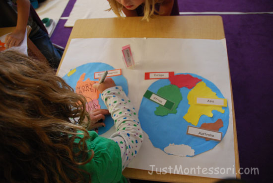 The older child writing the name of each continent on her map.